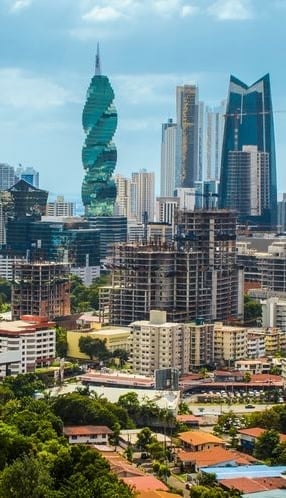 Modern cityscape with distinctive twisted high-rise buildings and skyscrapers against a blue sky with residential buildings and green spaces in foreground